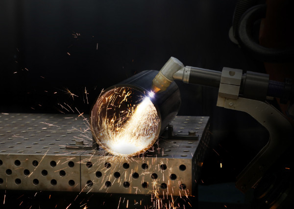 Plasmabrenner beim robotergestützten Schneiden eines Metallrohres. Am Schnittbereich entstehen zahlreiche Funken.